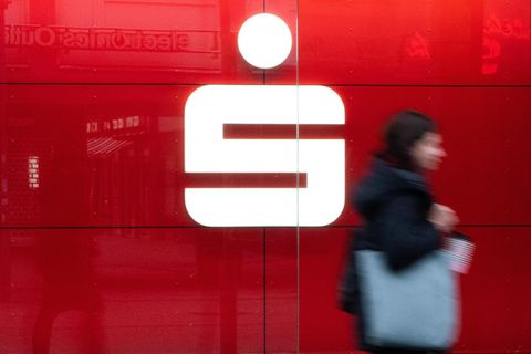 Logo der Bank Sparkasse auf rotem Hintergrund und Frau läuft davor