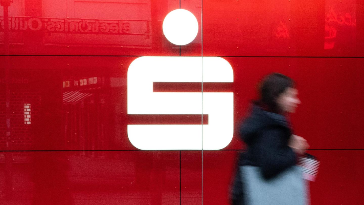 Logo der Bank Sparkasse auf rotem Hintergrund und Frau läuft davor