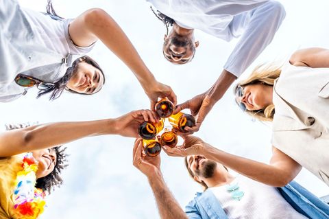 Alkohol: eine Gruper junger Menschen stößt mit Bierflaschen an