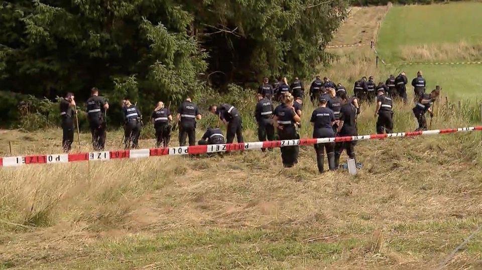 Polizisten durchsuchen ein Feld