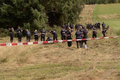 Polizisten durchsuchen ein Feld