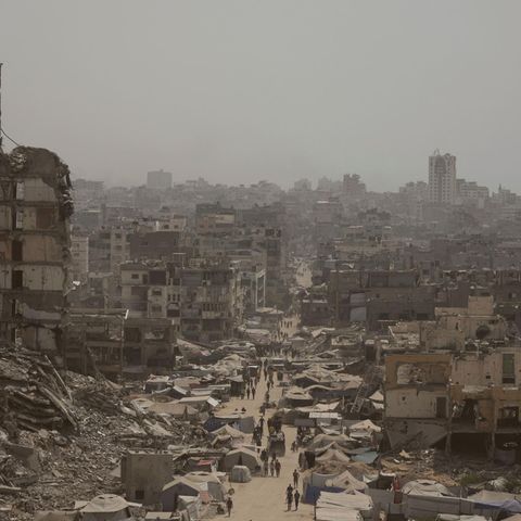 People walk along a street in the city of Gaza, which is surrounded by destroyed buildings