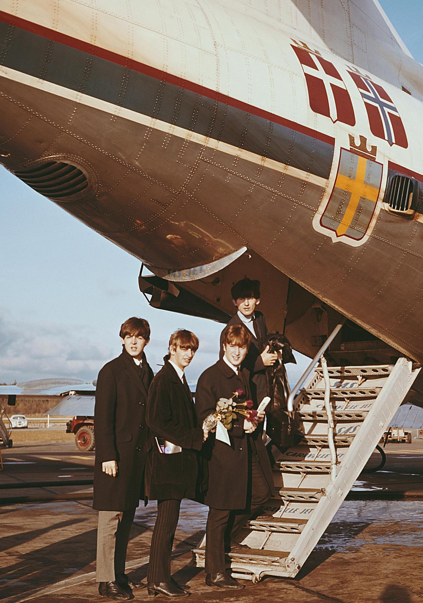 Die Beatles beim Einstieg in ein Flugzeug