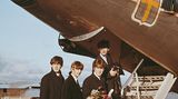 Die Beatles beim Einstieg in ein Flugzeug