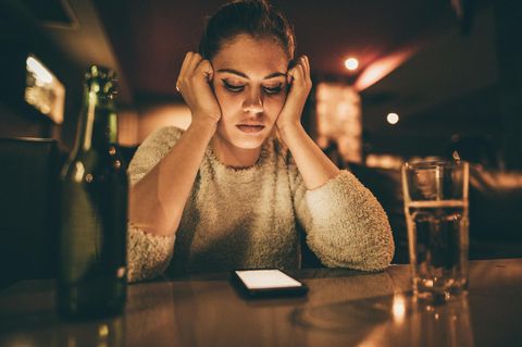 Love Scam: Eine Frau sitzt alleine in einer Bar