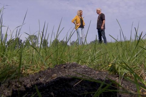 Ein Landwirt unterhält sich mit einer Frau neben einem Erdhügel