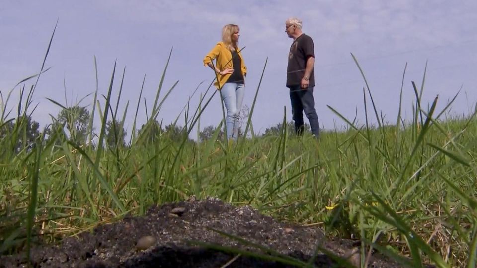 Ein Landwirt unterhält sich mit einer Frau neben einem Erdhügel