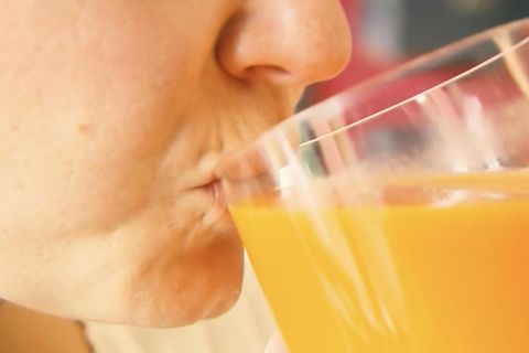 Eine Person nimmt einen schluck Orangensaft