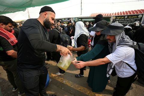 Freiwillige verteilen Wasser an Pilger im Irak