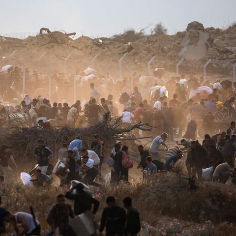 Palestinians carry aid packages from a GHF distribution center in Gaza