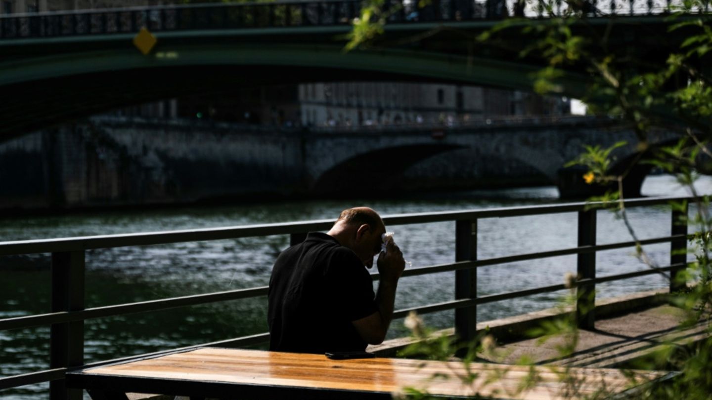 Mann in Paris tupft sich Schweiß von der Stirn