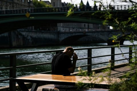 Mann in Paris tupft sich Schweiß von der Stirn