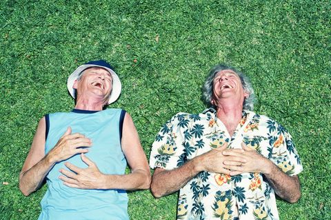 Zwei ältere Männer liegen lachend im Gras nebeneinander