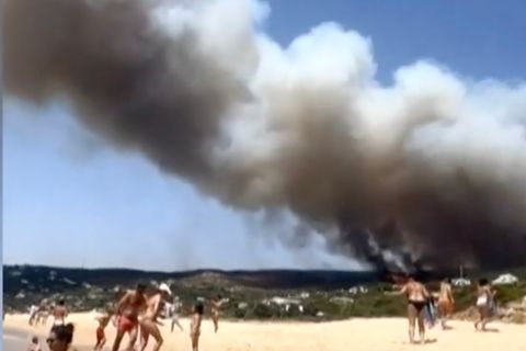 Menschen am Strand filmen Rauchschwaden.