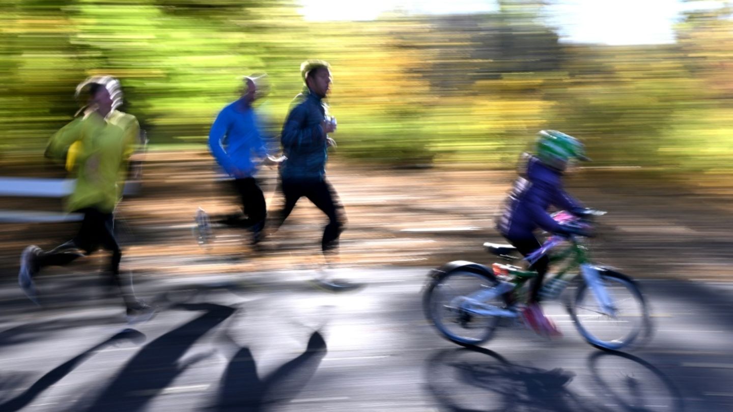 Kind auf Fahrrad neben Joggern