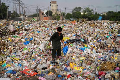 Ein Müllsammler sammelt wiederverwertbare Gegenstände, darunter Plastik, auf einer Mülldeponie