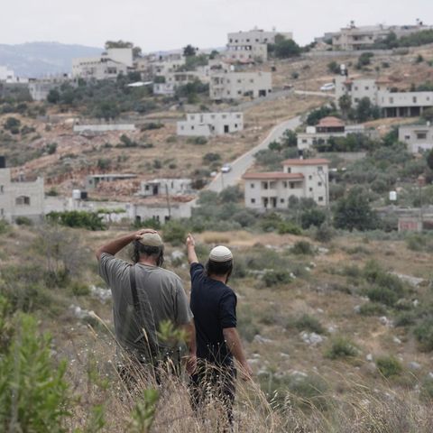 Israelische Siedler stehen vor einem Dorf im Westjordanland