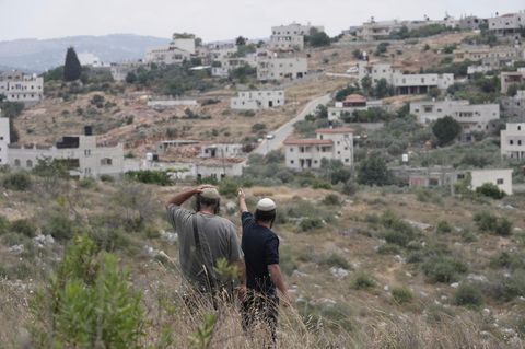 Israelische Siedler stehen vor einem Dorf im Westjordanland