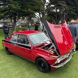 Eine Reihe von roten Alpina BMW 2002 auf einer Wiese