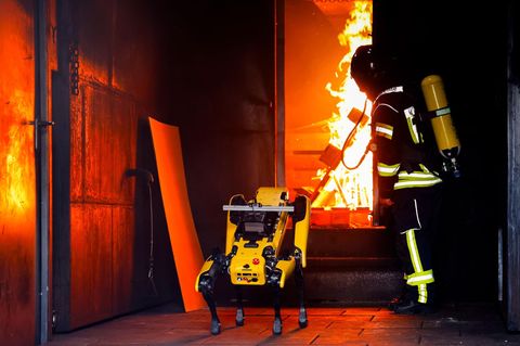 Der KI-Roboter "Byte" wird von einem Feuerwehrmann beim Löschen eines Containerbrandes beaufsichtigt
