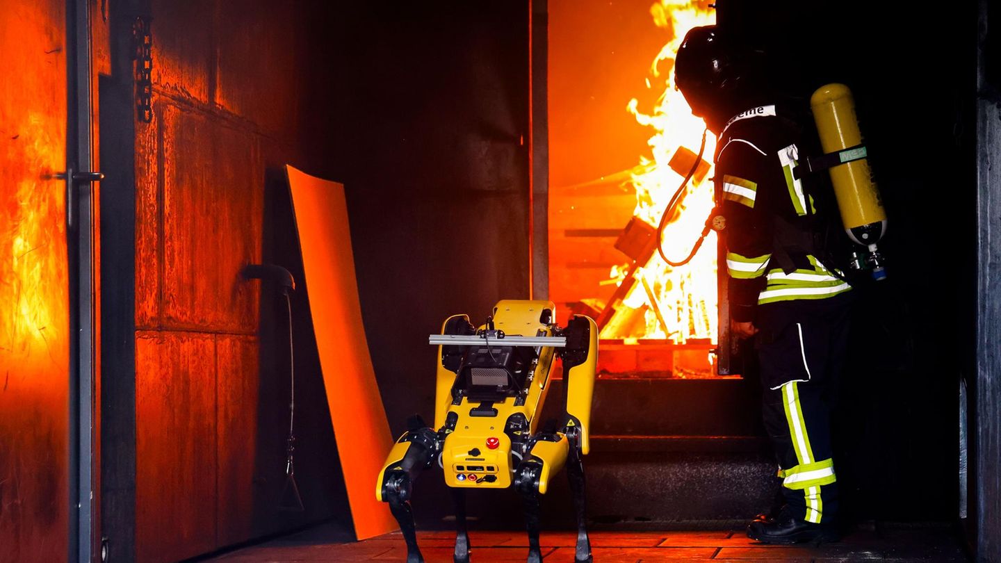 Der KI-Roboter "Byte" wird von einem Feuerwehrmann beim Löschen eines Containerbrandes beaufsichtigt