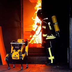 Der KI-Roboter "Byte" wird von einem Feuerwehrmann beim Löschen eines Containerbrandes beaufsichtigt