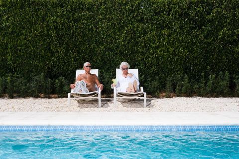 Ein älteres Ehepaar sonnt sich an einem Pool