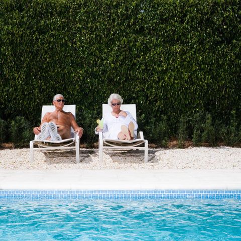 Ein älteres Ehepaar sonnt sich an einem Pool