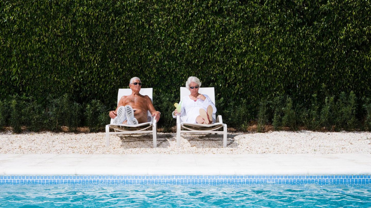 Ein älteres Ehepaar sonnt sich an einem Pool