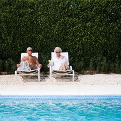 Ein älteres Ehepaar sonnt sich an einem Pool