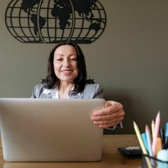 Gehalt: Frau sitzt lächelnd vor einem Laptop