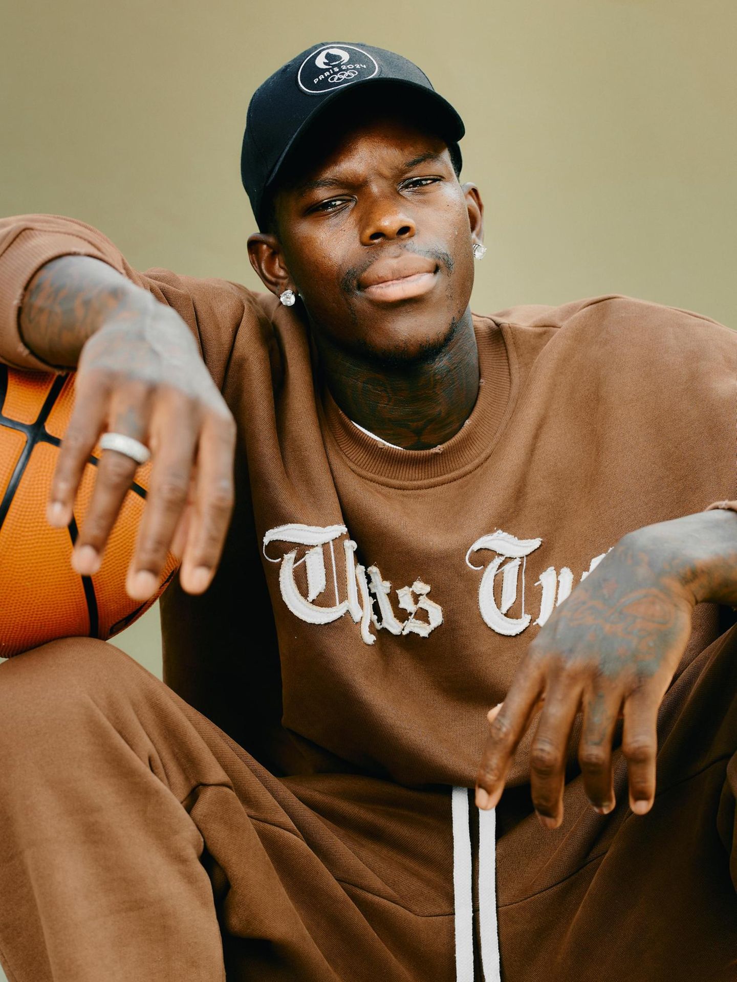 Dennis Schröder sitzt mit Basketball unter dem Arm auf dem Basketballplatz im Prinzenpark