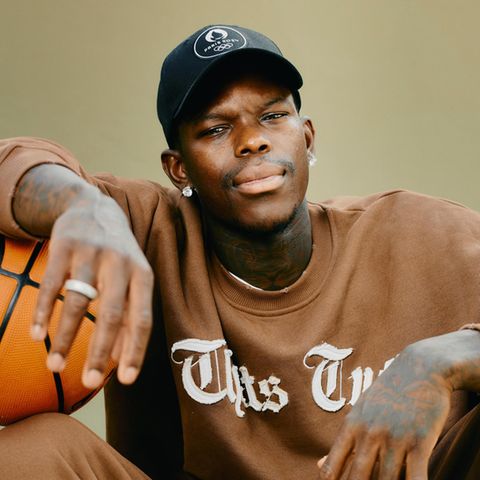 Dennis Schröder sitzt mit Basketball unter dem Arm auf dem Basketballplatz im Prinzenpark