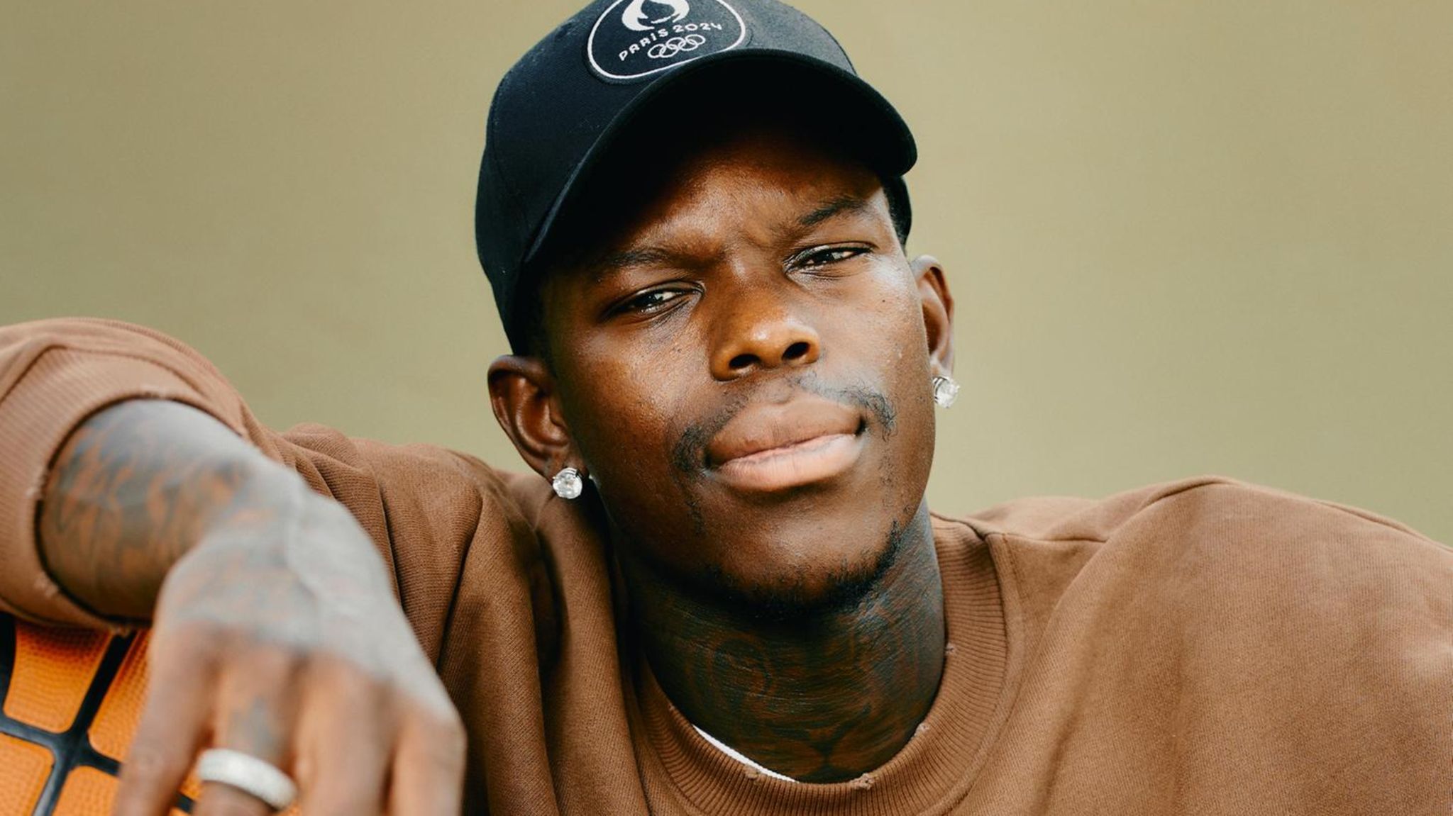 Dennis Schröder sitzt mit Basketball unter dem Arm auf dem Basketballplatz im Prinzenpark
