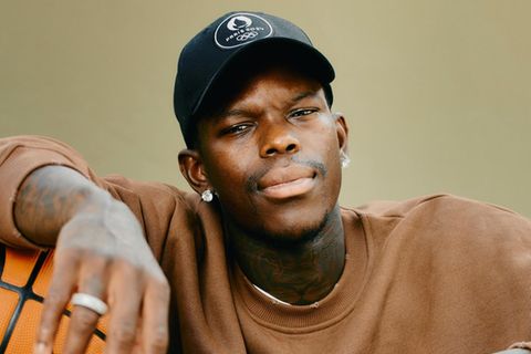 Dennis Schröder sitzt mit Basketball unter dem Arm auf dem Basketballplatz im Prinzenpark