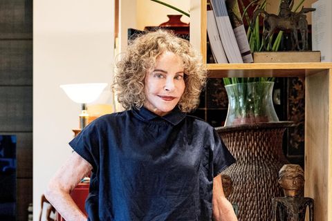 Sydne Rome in ihrer Wohnung in Rom, sie trägt roten Lippenstift und eine blaue Bluse