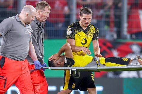 Ein verzweifelter Yan Couto vom BVB hält sie die Hände vor das Gesicht, während er auf einer Trage vom Platz getragen wird