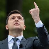 Selenskyj im Anzug mit Hand nach oben gereckt