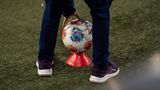 Bundesliga: Ein Ballkind legt einen Fußball auf ein Hütchen