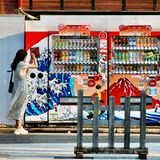 Eine Frau fotografiert mit ihrem Smartphone zwei Getränkeautomaten in Tokio