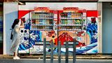 Eine Frau fotografiert mit ihrem Smartphone zwei Getränkeautomaten in Tokio
