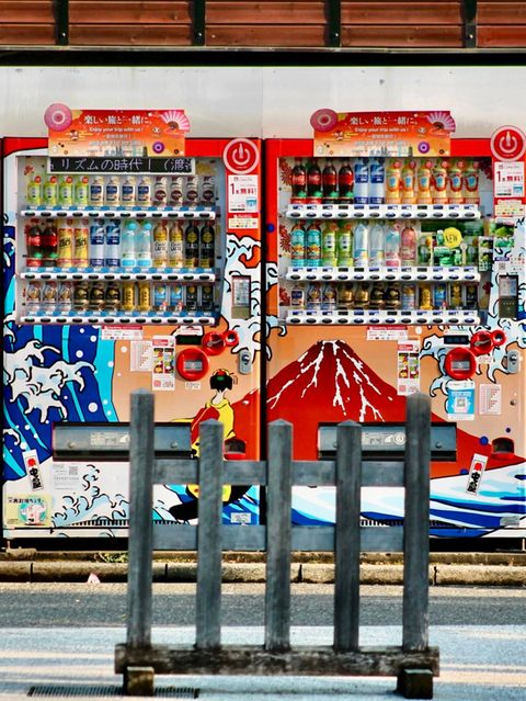 Eine Frau fotografiert mit ihrem Smartphone zwei Getränkeautomaten in Tokio