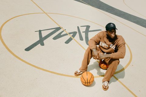 Dennis Schröder sitzt im Braunschweiger Prinzenpark auf einem Basketball