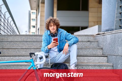 Ein junger Mann sitzt auf einer Treppe und hat Kopfhörer um den Hals: Heute gibt es mit dem Sommerhit den neuen Ohrwurm