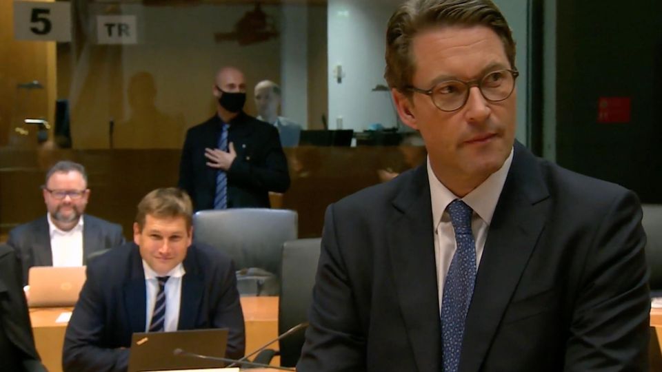 Scheuer steht im Gerichtssaal, im Anzug gekleidet.