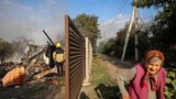 Sknyliv, Ukraine. Während ein Feuerwehrmann die Einschlagstelle einer russischen Rakete begutachtet, scheint die ältere Frau eher ungerührt vorbeizugehen. Entweder ist sie desinteressiert oder sie hat schon alles gesehen, was sie sehen wollte