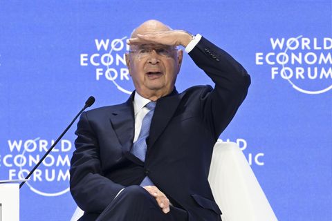 Klaus Schwab sitzt auf einem Podium des Weltwirtschaftsforums in Davos und sieht ins Publikum