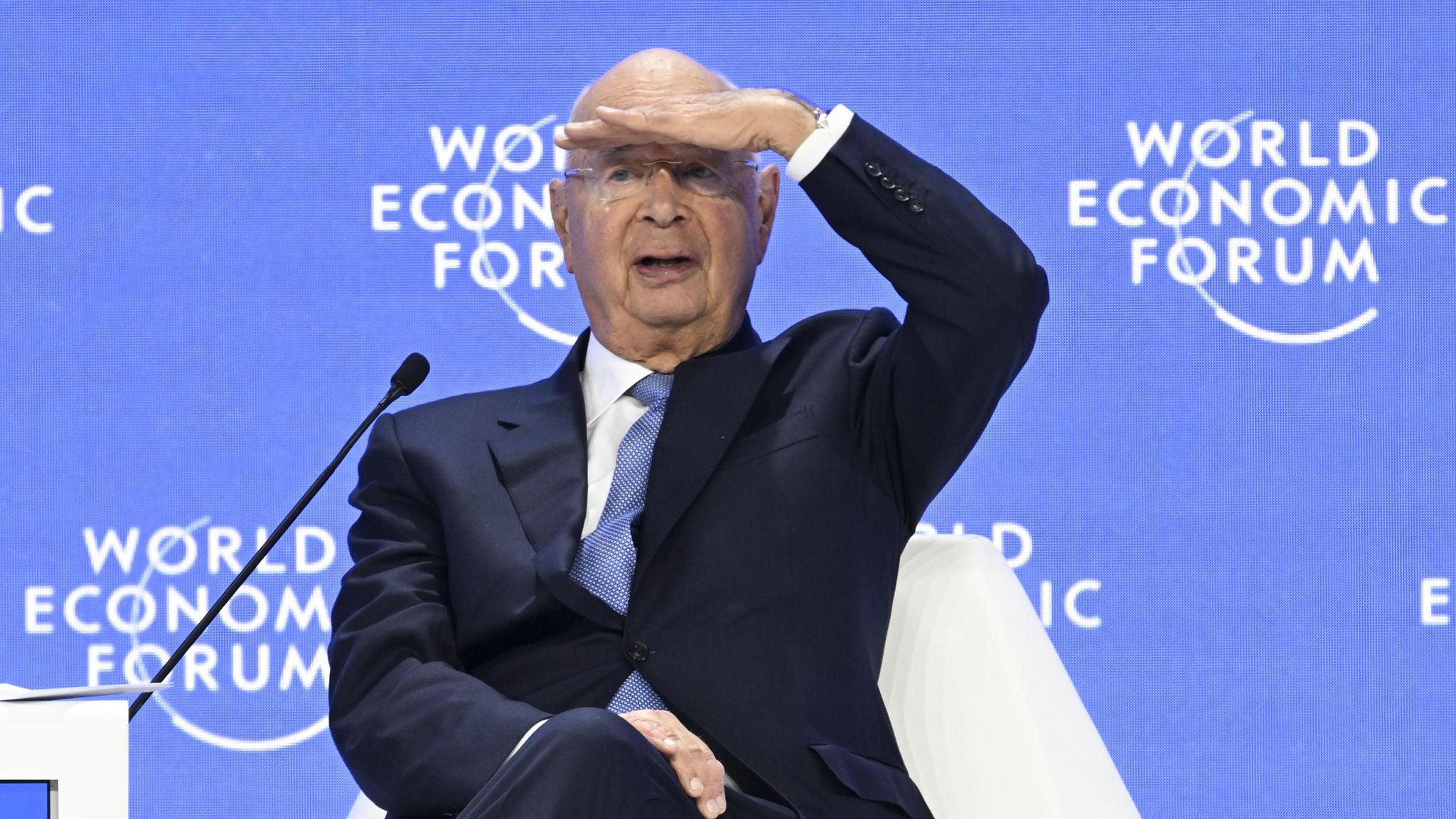 Klaus Schwab sitzt auf einem Podium des Weltwirtschaftsforums in Davos und sieht ins Publikum