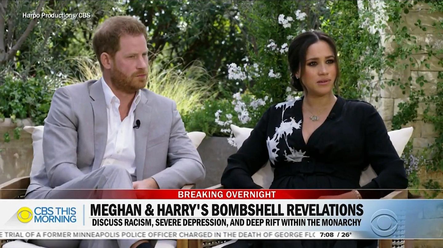 Prinz Harry im hellgrauen Anzug neben Ehefrau Meghan bei einem Interview