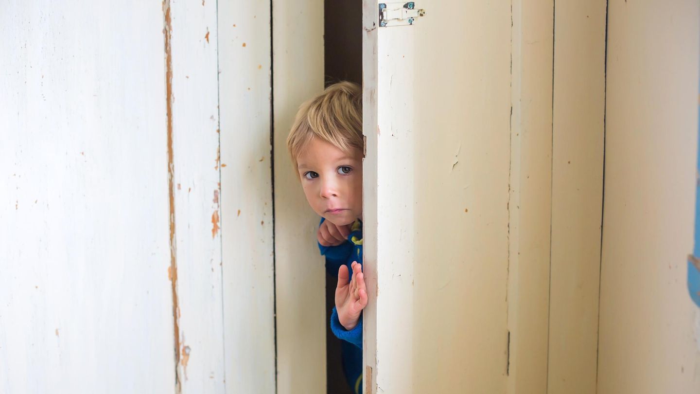 Kinder: Ein kleiner Junge guckt durch einen Türspalt